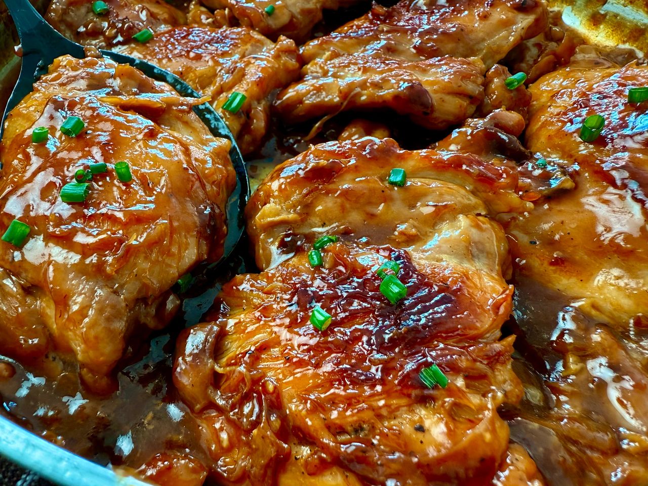 teriyaki chicken in a pan with a serving spoon