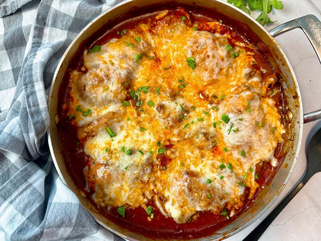 chicken thighs and marinara sauce with cheese in a pan