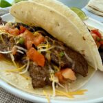 steak street tacos on a white plate with lime garnish