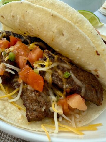 steak street tacos on a white plate with lime garnish