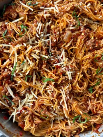 pasta bolognese in a silver pan with a black spoon