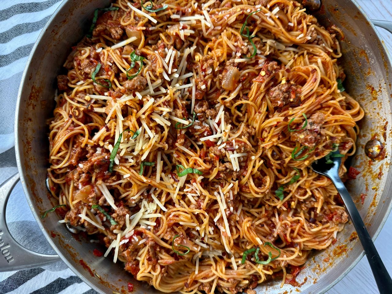 pasta bolognese in a silver pan with a black spoon