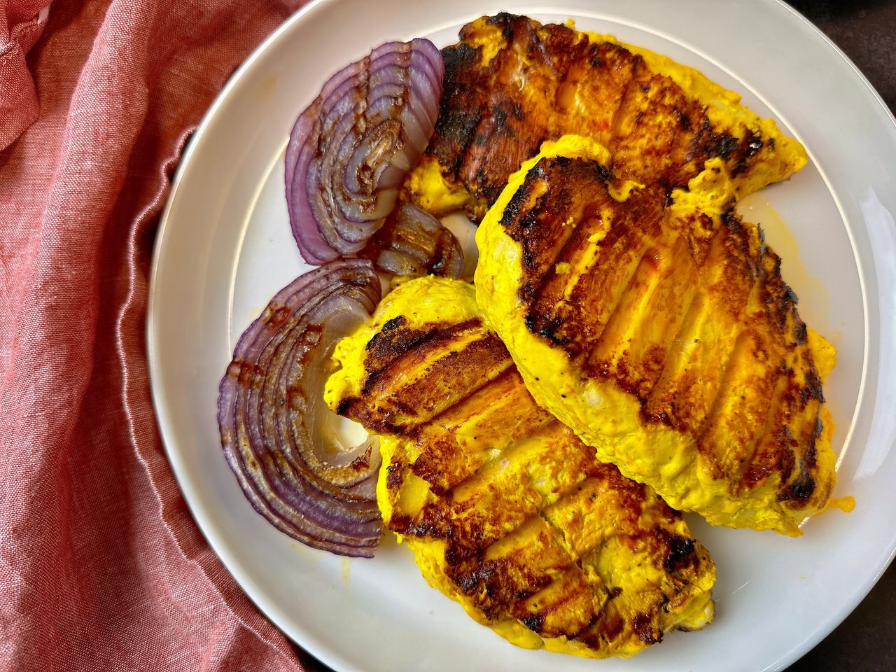 saffron chicken and red onion on a white plate