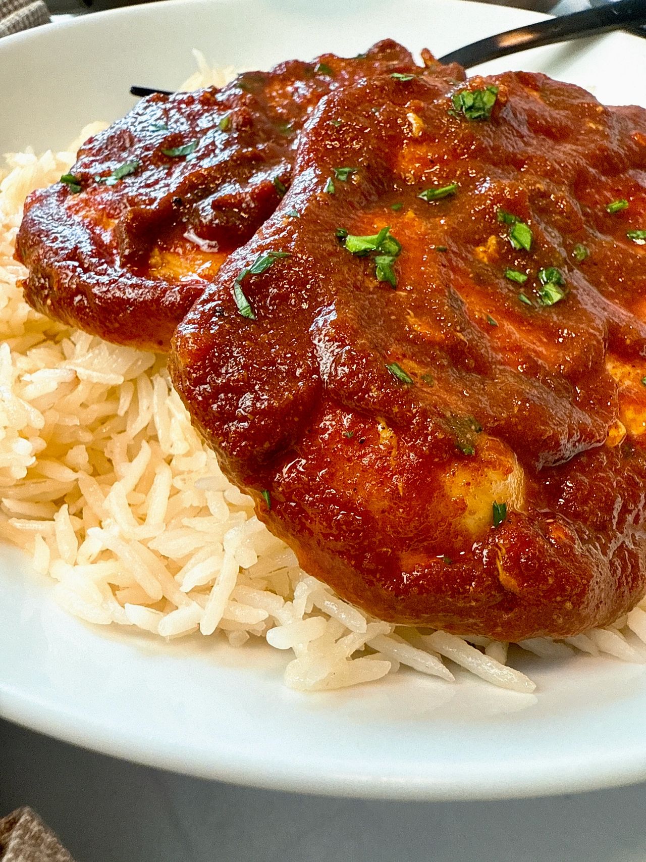 chicken with enchilada sauce over rice on a white plate