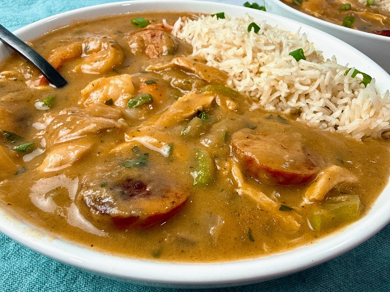 Cajun gumbo and rice in a white bowl with a black spoon