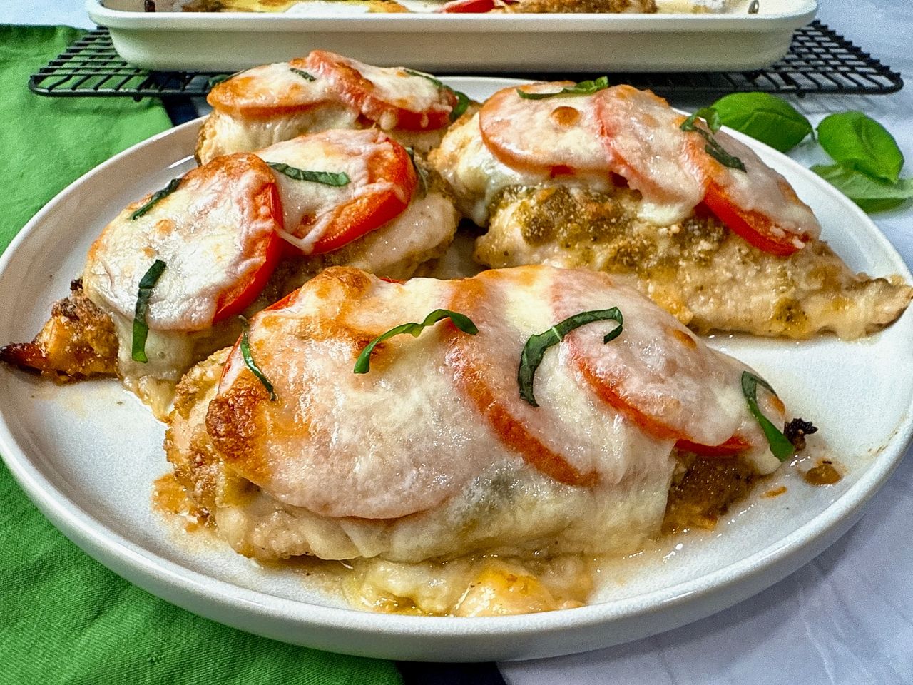 baked chicken with cheese and tomatoes on a white plate