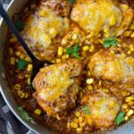 salsa chicken with cheese in a silver pan with a black spoon