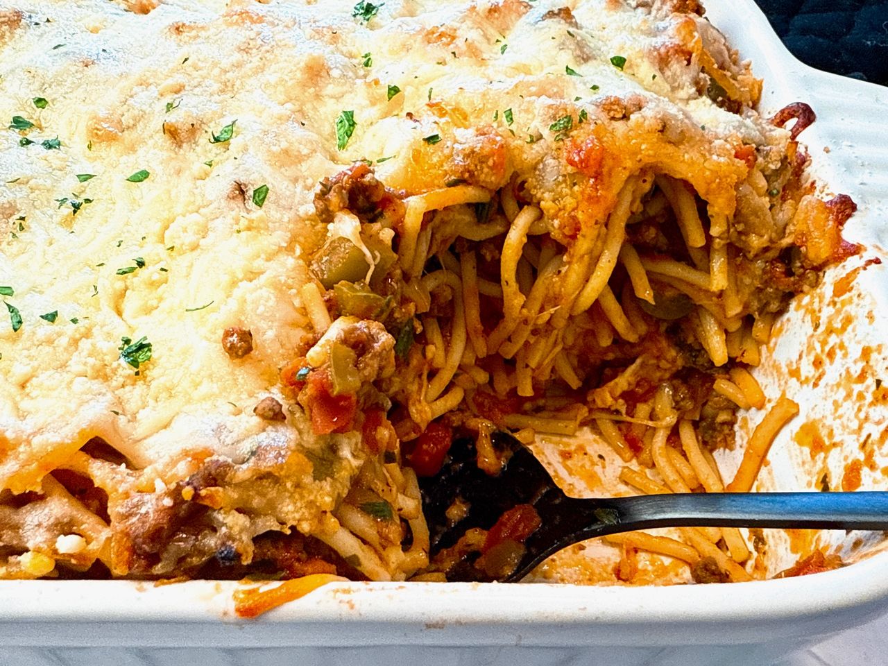 baked spaghetti in a baking dish with a black spoon