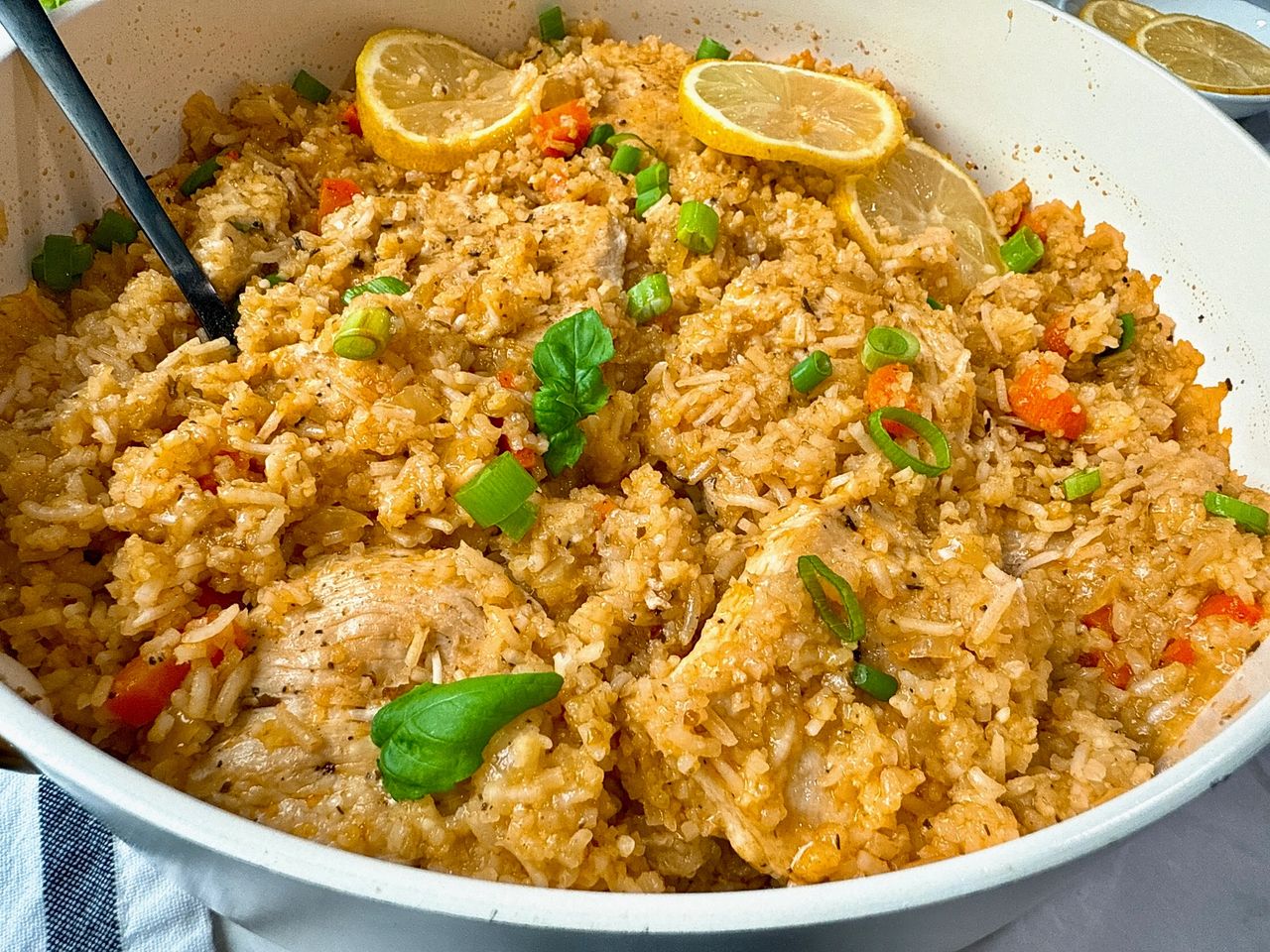 chicken and rice in a white saucepan with lemon garnish