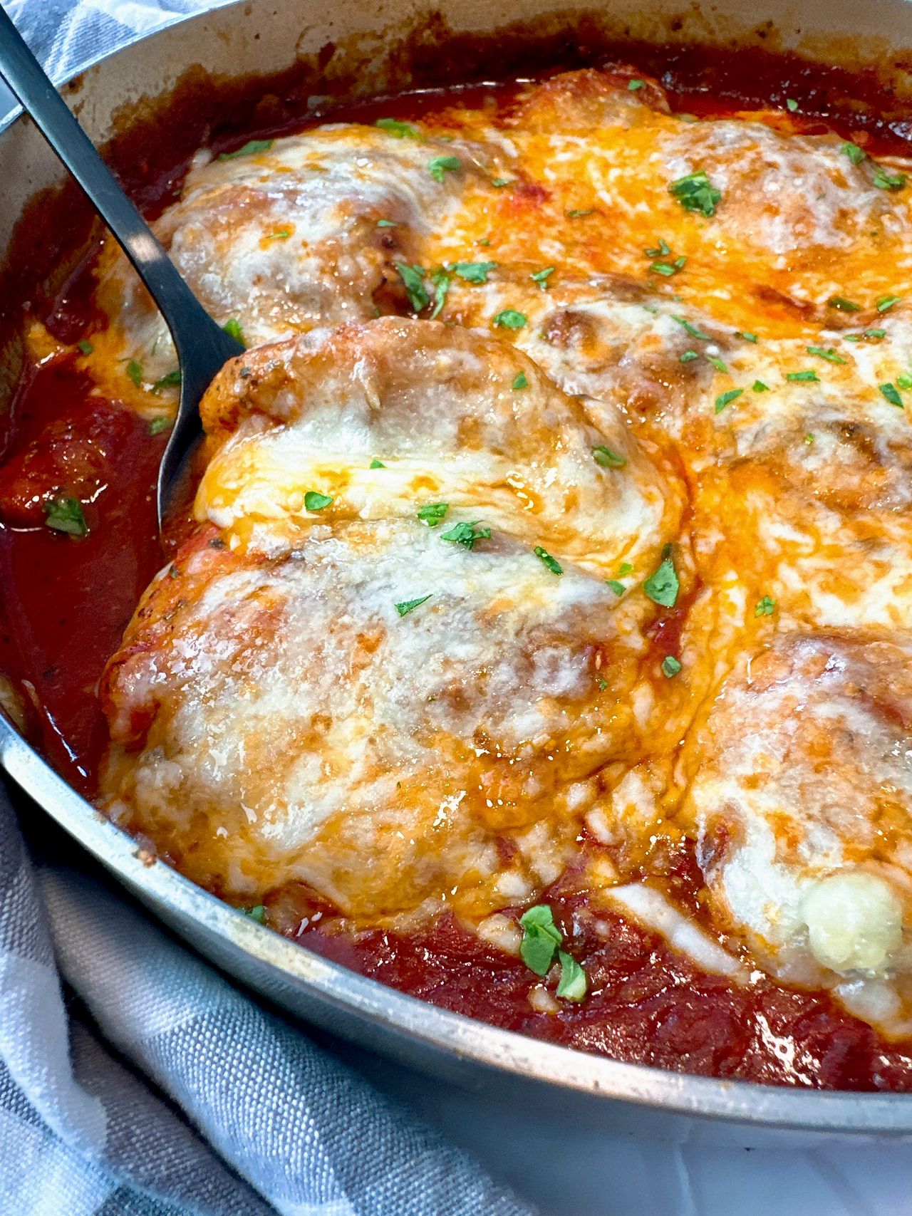 chicken thighs and marinara sauce with cheese in a pan