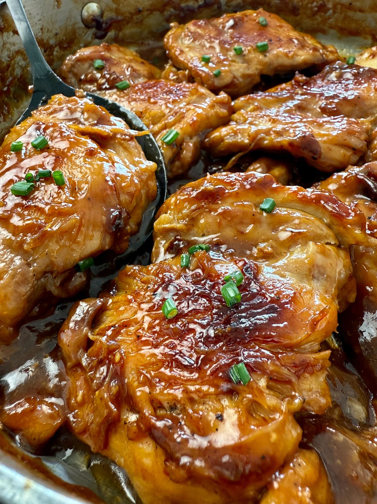 teriyaki chicken in a pan with a serving spoon