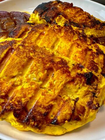 saffron chicken and red onion on a white plate