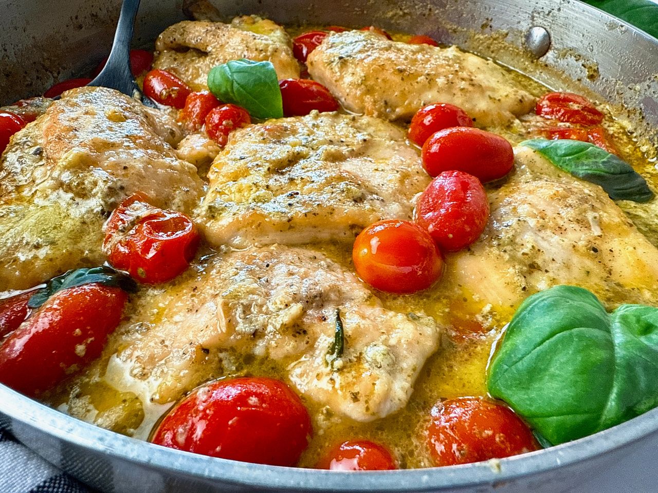 chicken and grape tomatoes with pesto in a silver pan