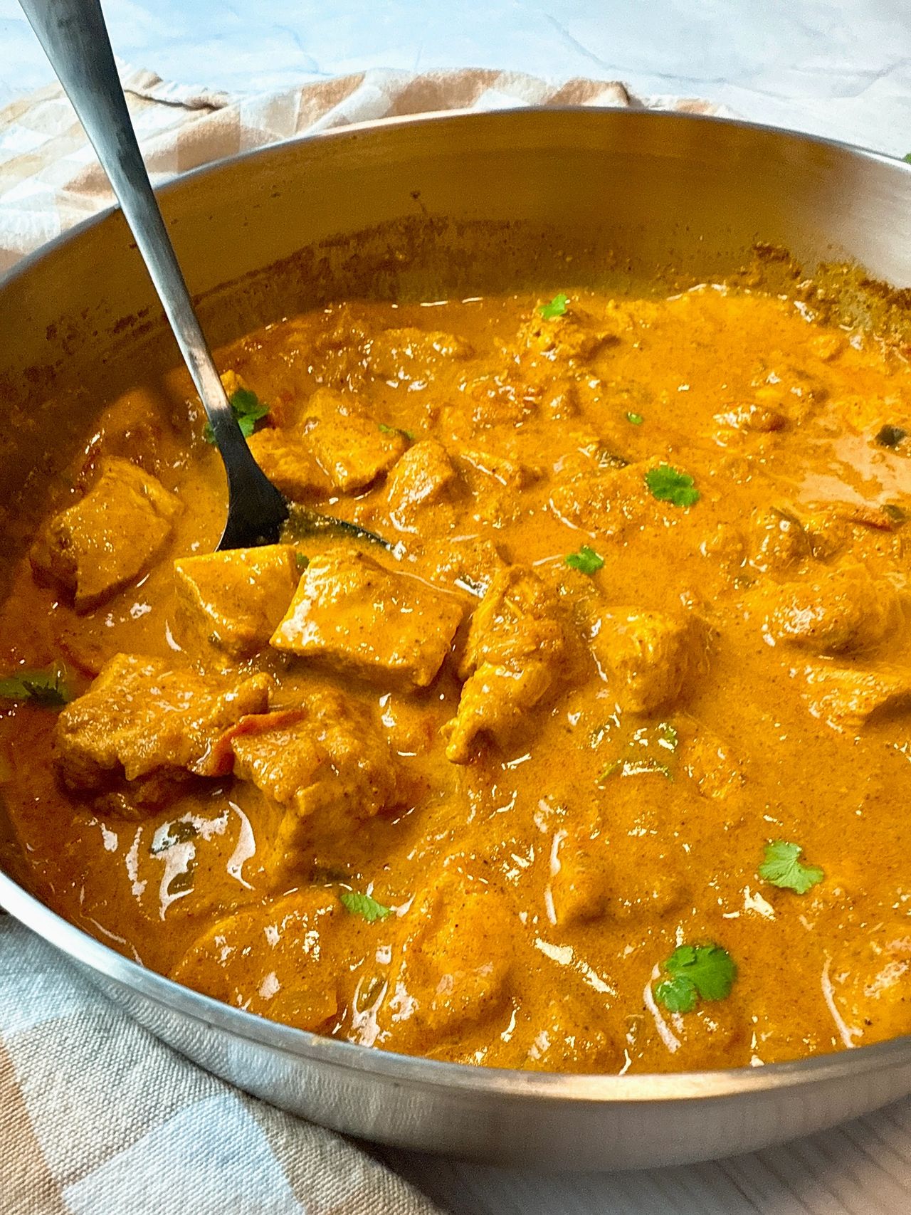 chicken curry topped with cilantro in a silver pan