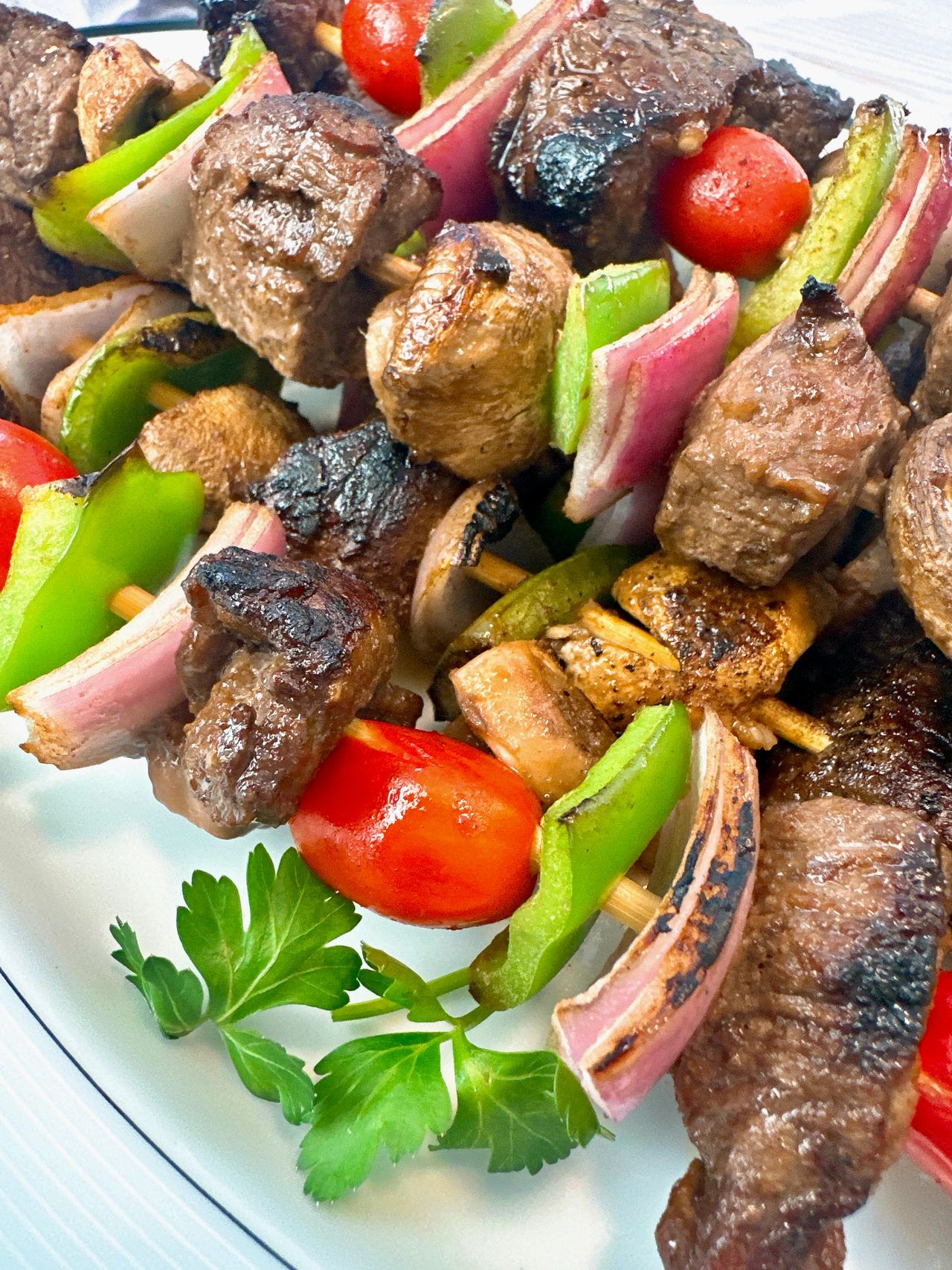 beef and vegetable kebabs on a white serving plate