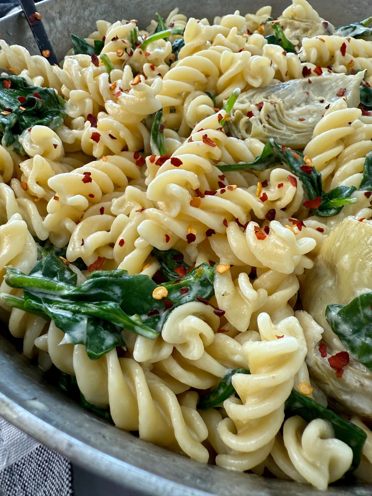 pasta with spinach and artichoke hearts in a skillet