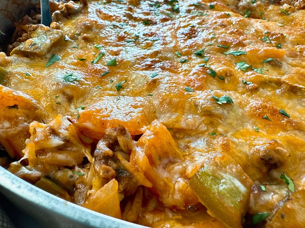 ground beef and rice covered with melted cheddar cheese in a deep skillet
