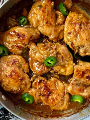 chicken thighs and jalapeno peppers in a silver pan