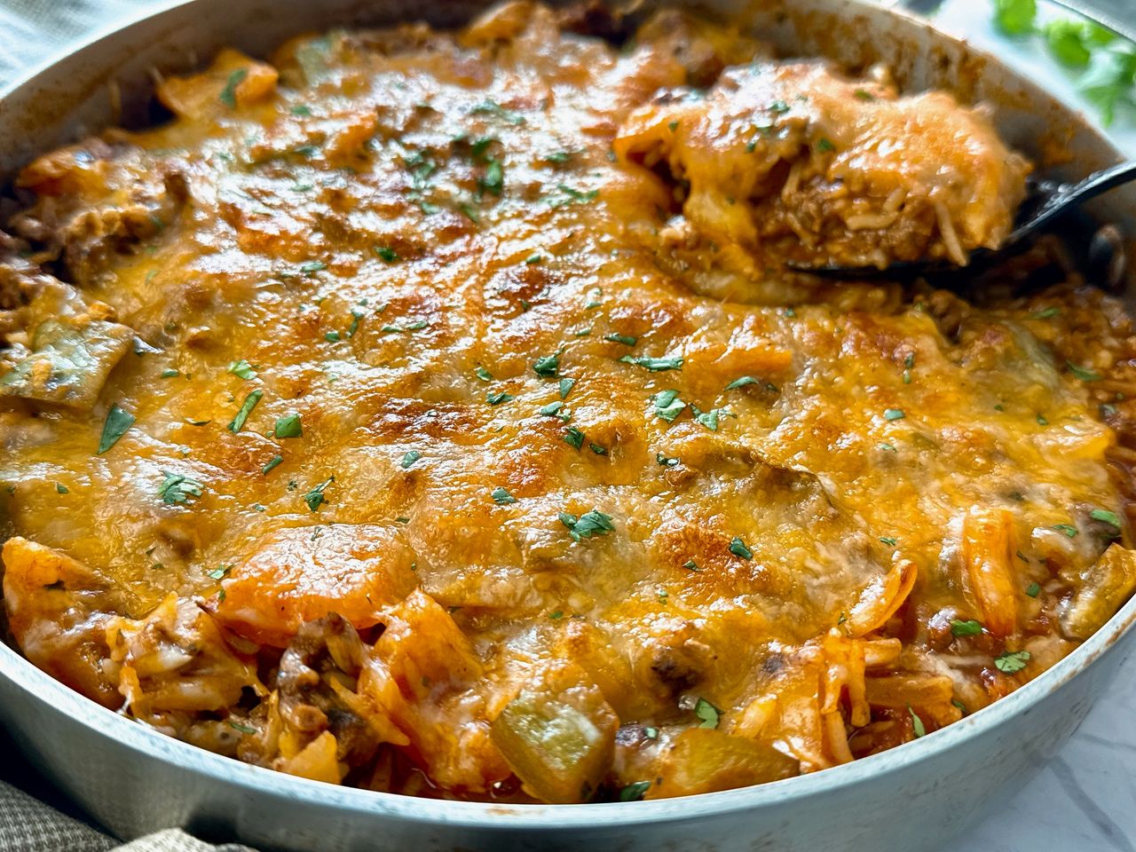 ground beef and rice covered with melted cheddar cheese in a deep skillet
