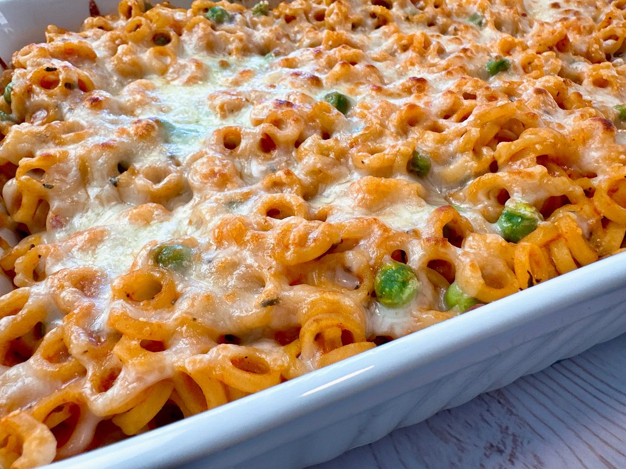 baked pasta rings with sauce and cheese in a white casserole dish