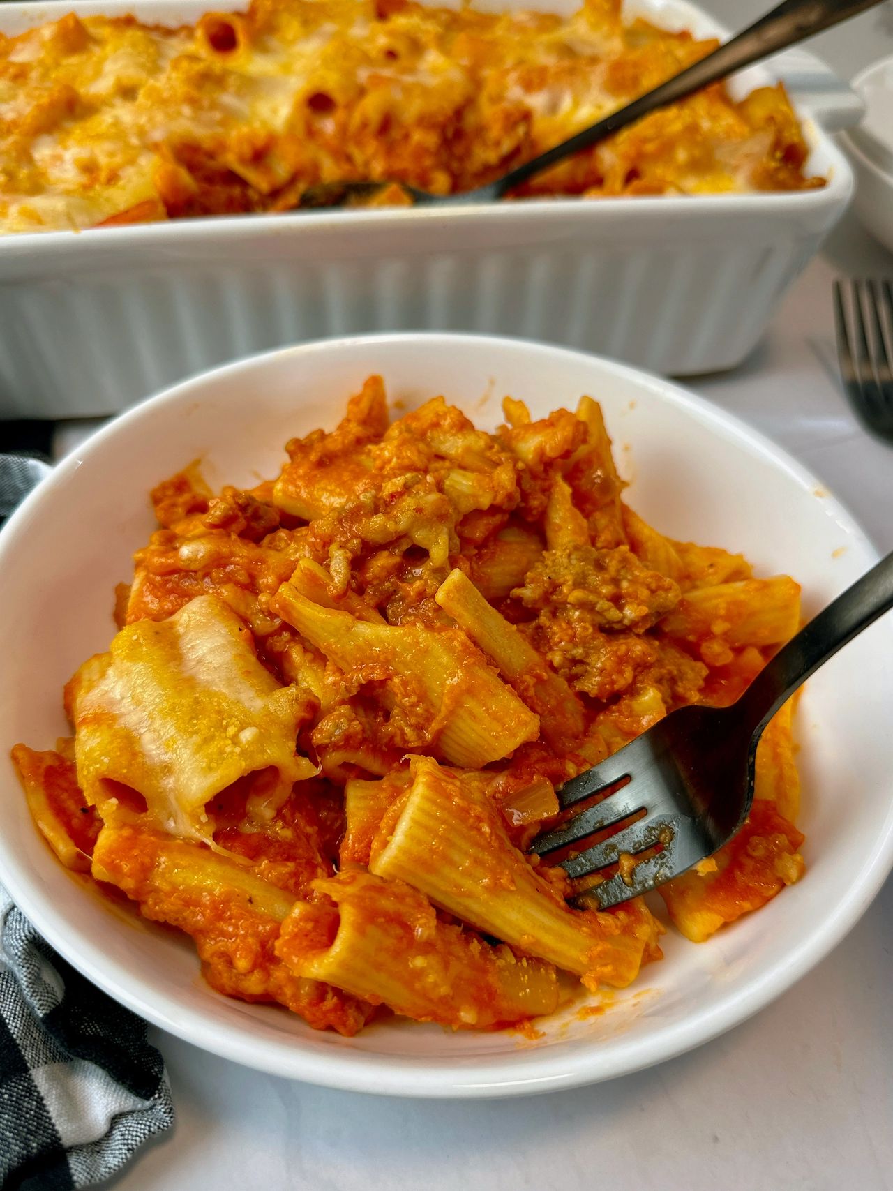 pasta and sausage in a casserole dish and white bowl