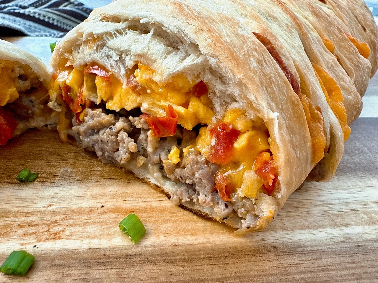 breakfast braid with eggs, cheese and sausage on a wooden cutting board