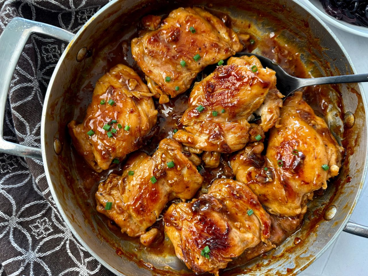 teriyaki chicken in a pan with a serving spoon