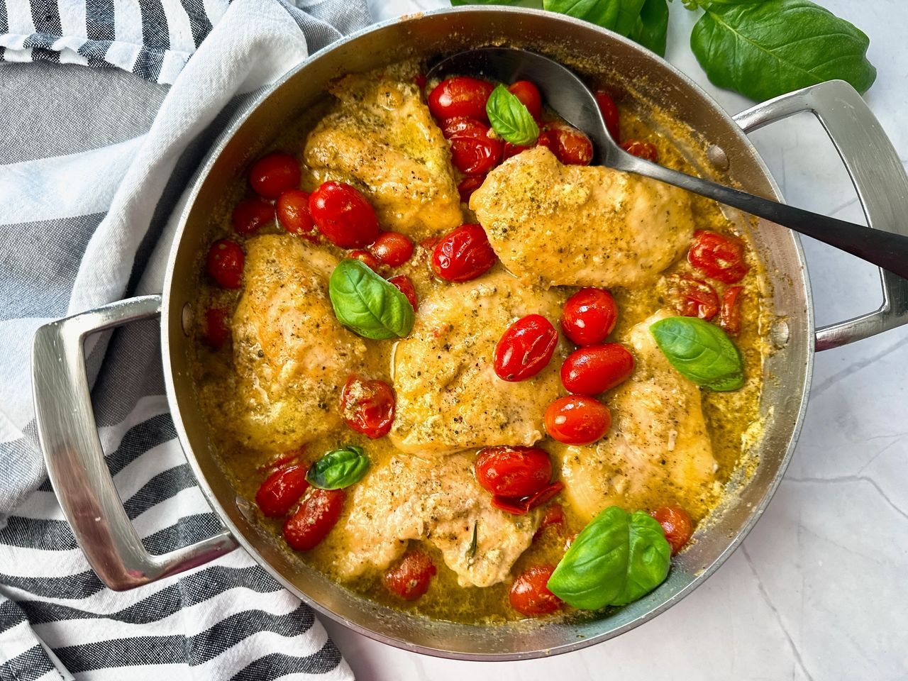 chicken and grape tomatoes with pesto in a silver pan