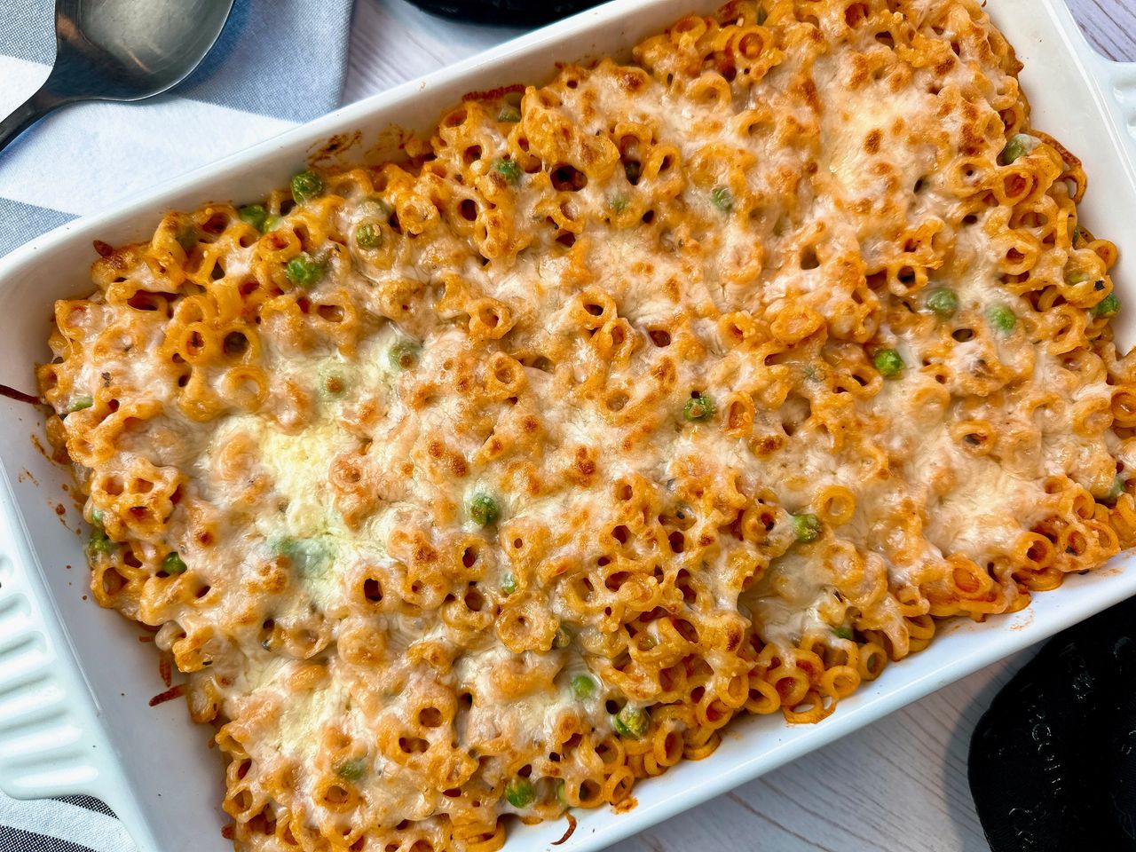 baked pasta rings with sauce and cheese in a white casserole dish