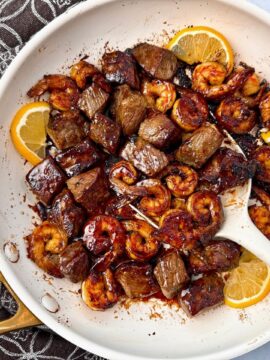 steak and shrimp in a white skillet