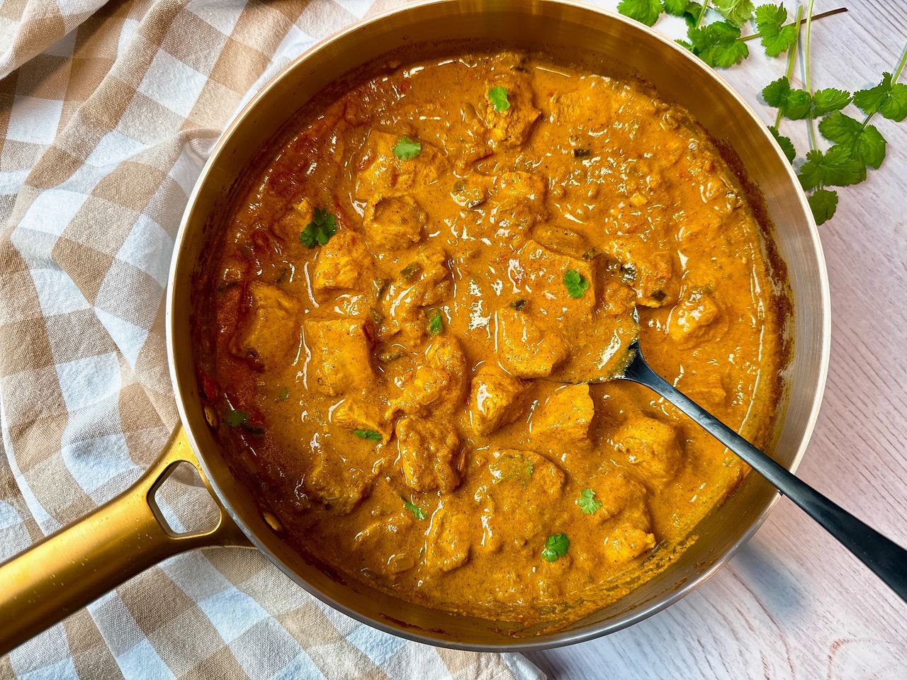chicken curry topped with cilantro in a silver pan