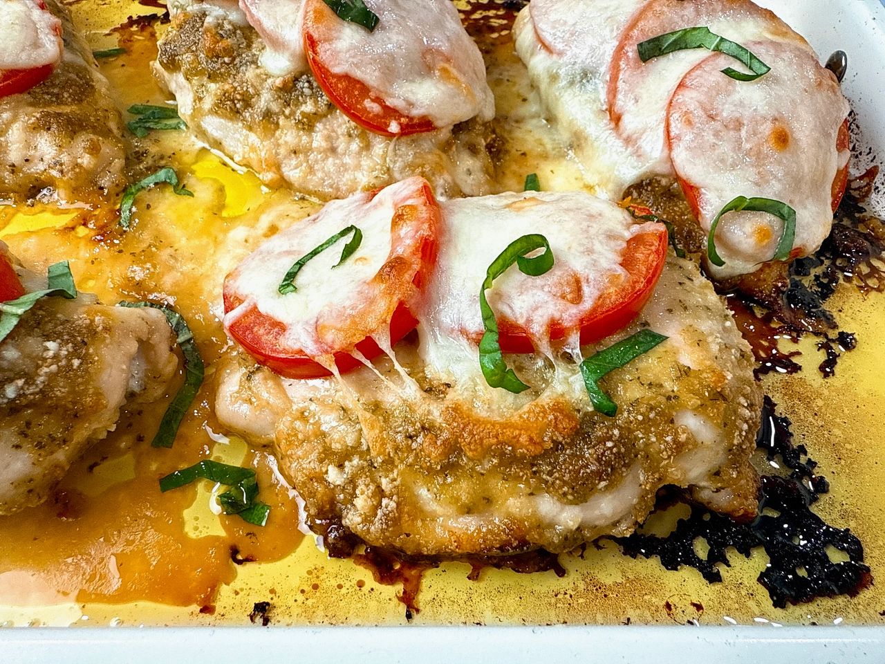 baked chicken with cheese and tomatoes on a white plate