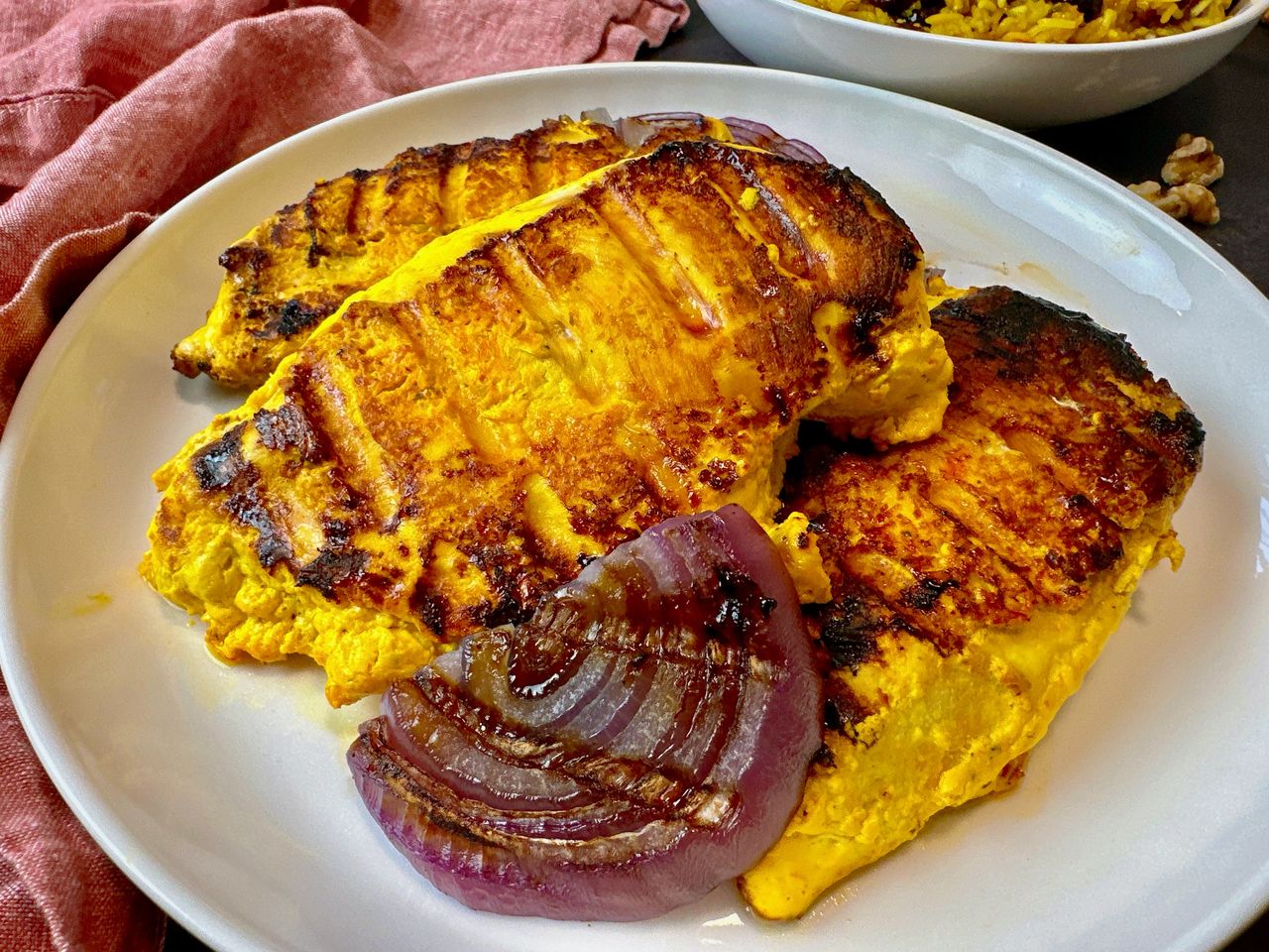 saffron chicken and red onion on a white plate