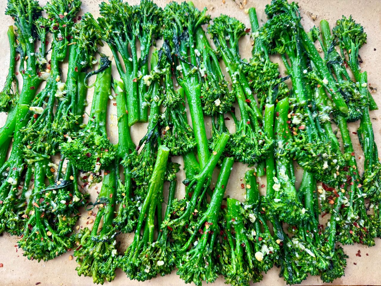 broccolini and red pepper flakes on a parchment paper lined baking sheet
