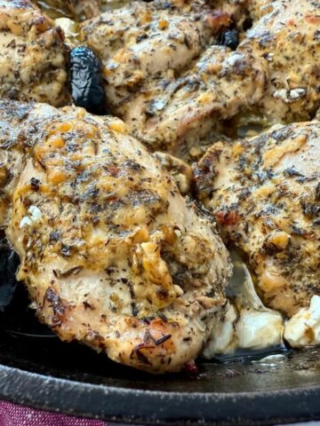 chicken thighs in a cast iron skillet with feta and olives