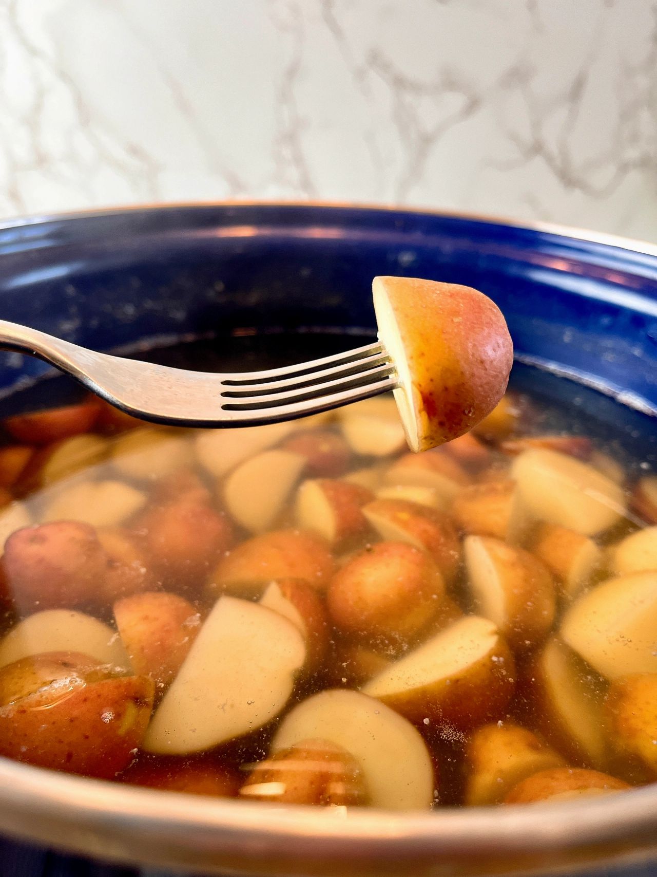 potato on a fork over a pot