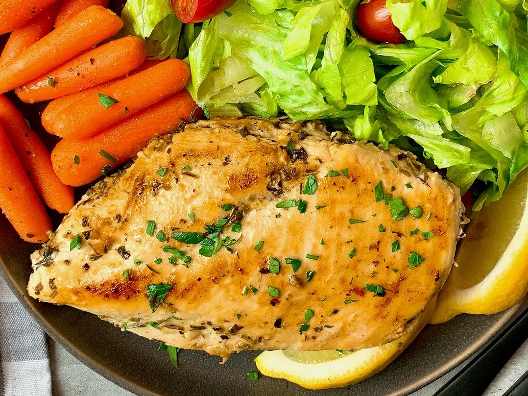 chicken breast on a plate with vegetables and lemon