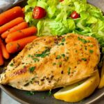chicken breast on a plate with vegetables and lemon