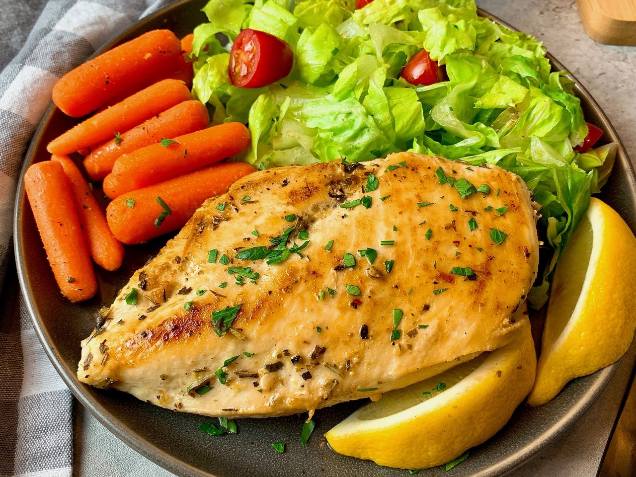 chicken breast on a plate with vegetables and lemon